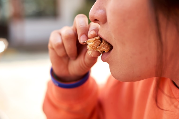Young woman puts a piece of muffin in her mouth stress eater eating